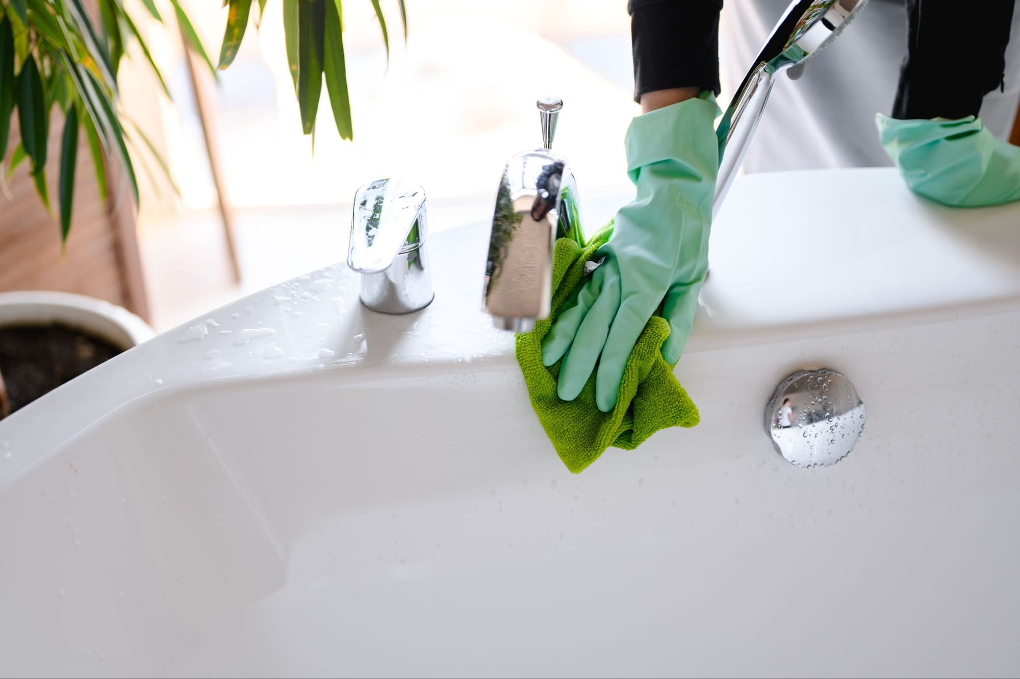 a person scrubbing the faucet with green gloves and green cloth