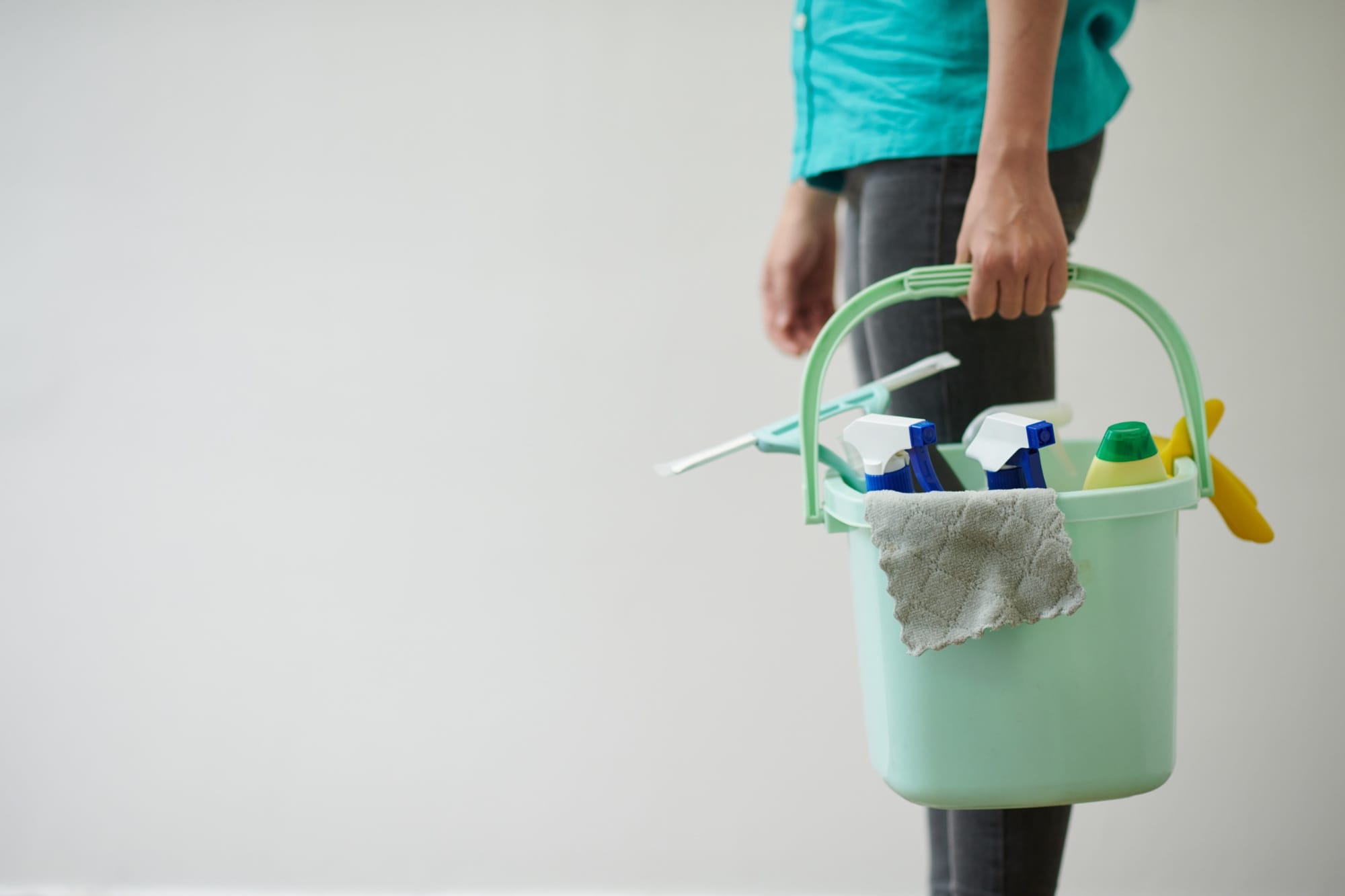 a person holding a bucket that is full with cleaning products