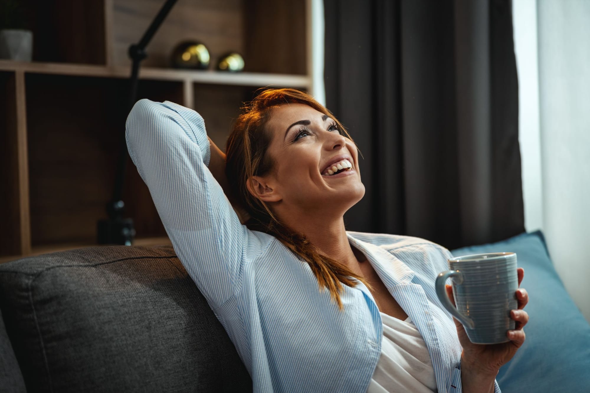 a woman relaxing on her couch while holding a mug