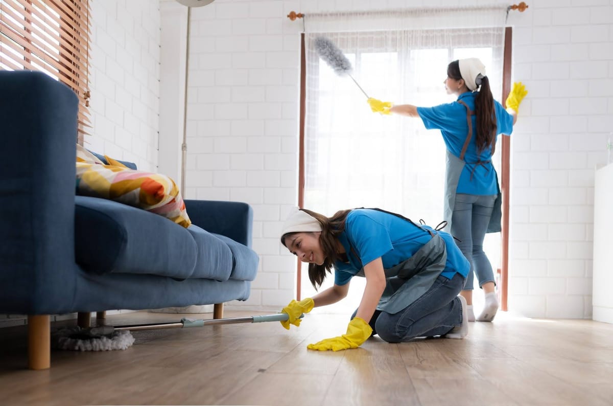 Professional cleaners providing weekly cleaning services, mopping and dusting a living room