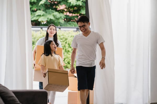 A happy family carrying cardboard boxes into their bright new home